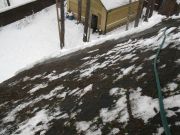 Процесс удаления льда при помощи горячей воды с крыши коттеджа